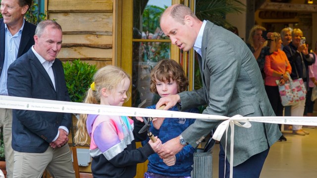 Article thumbnail: LOSTWITHIEL, CORNWALL - JULY 10: Prince William, Prince of Wales helps brother and sister James and Violet Scott to cut the ribbon as he visits The Duchy Of Cornwall Nursery to open The Orangery restaurant on July 10, 2023 in Lostwithiel, United Kingdom. Prince William visits The Duchy Of Cornwall Nursery to open The Orangery restaurant, which has been built as part of a nine-month extension project to create sustainable visitor spaces at the garden centre. (Photo by Hugh Hastings - WPA Pool / Getty Images)