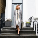 Article thumbnail: Businesswoman in her 30s leaving home in the morning, looking sideways and carrying briefcase, she is descending steps outside front door and setting off on her morning commute