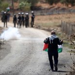 Article thumbnail: NABLUS, WEST BANK - SEPTEMBER 15: A Palestinian man holds the Palestinian flag in front of Israeli forces as they demonstrate against construction of Jewish settlements in village of Qaryut of Nablus, West Bank on September 15, 2023. (Photo by Issam Rimawi/Anadolu Agency via Getty Images)