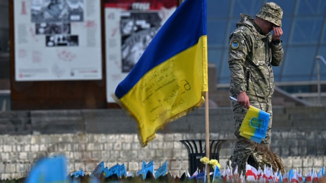 Article thumbnail: A serviceman mourns next to a Ukrainian flag at a makeshift memorial for fallen soldiers at Independence Square in Kyiv, on November 10 2023, amid the Russian invasion of Ukraine. (Photo by Sergei SUPINSKY / AFP) (Photo by SERGEI SUPINSKY/AFP via Getty Images)